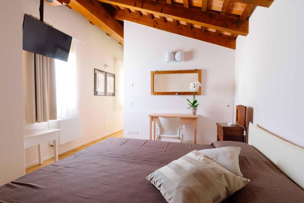 sypialnia z dużym łóżkiem i biurkiem w obiekcie B&B Mulino di Campese w mieście Campese