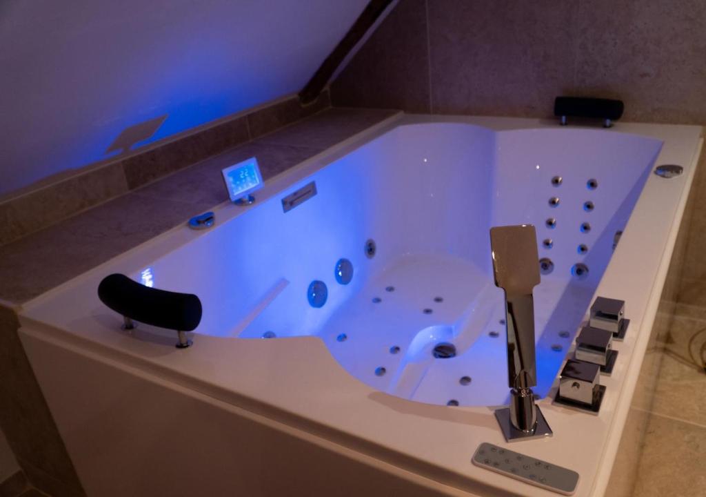 a large bath tub with a black chair in a room at Love Room Evasion Jacuzzi Sauna Hamamm in Saint-Cyr-sur-Loire