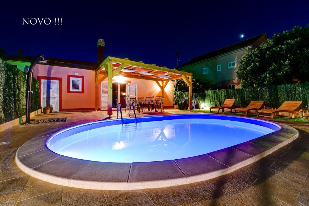 a large pool in a backyard at night at Holiday home Orange with heated pool and parking in Zadar