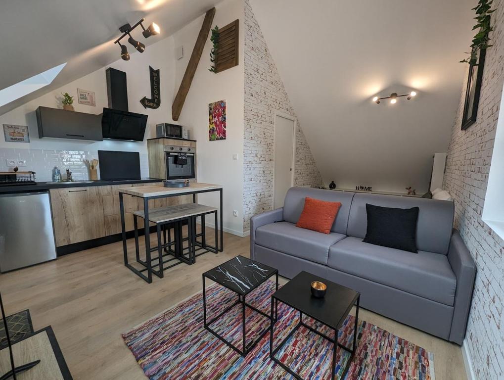 a living room with a couch and a kitchen at Le Studio Neo-Retro in Digoin