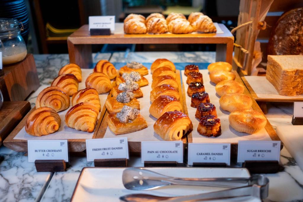 A labelled pastry station offering croissants, danishes, and other baked breakfast items.