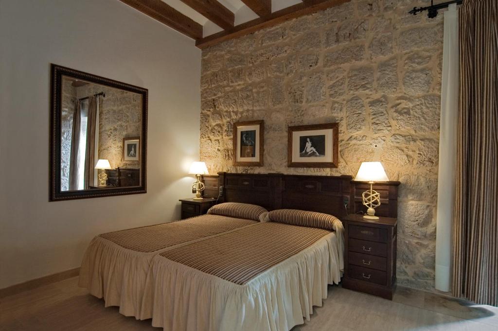 1 dormitorio con cama y pared de piedra en Señorio de Olmillos, en Olmillos de Sasamón