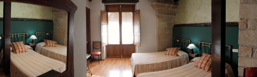 2 camas en una habitación con paredes verdes en Vivienda Turística Yamaries en Úbeda