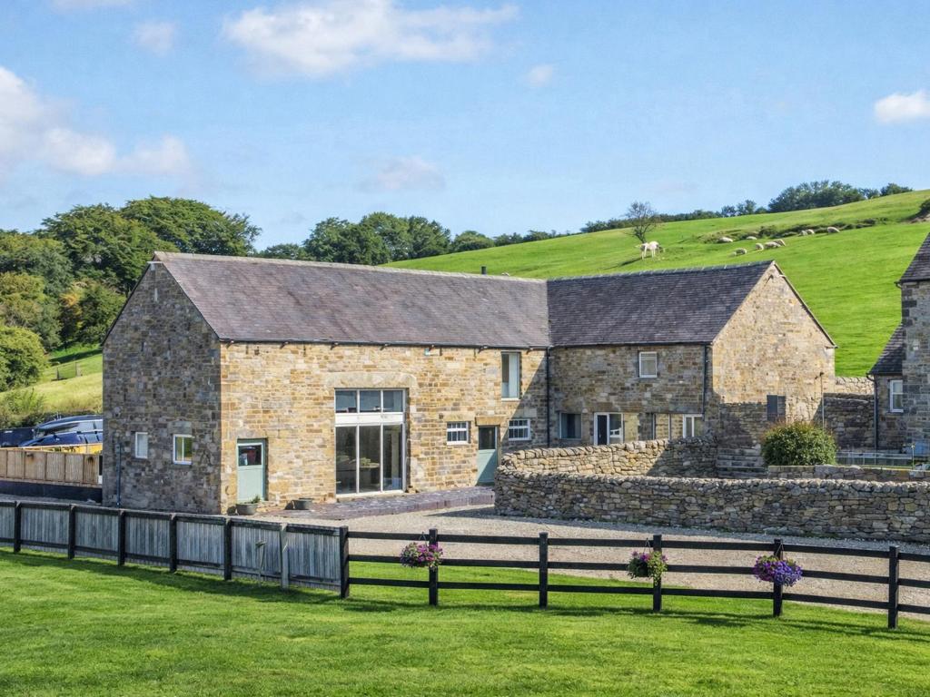 a stone house with a hill in the background at Pastures Barn in Leek