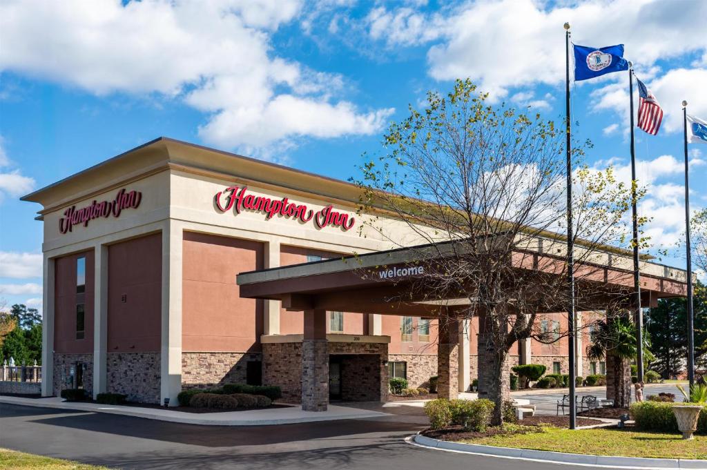a front view of a shopping center with two american flags at Hampton Inn South Hill in South Hill
