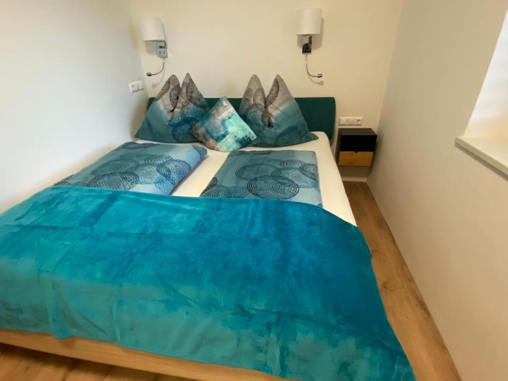 a bedroom with a bed with blue sheets and pillows at Haus Caré in Weissensee