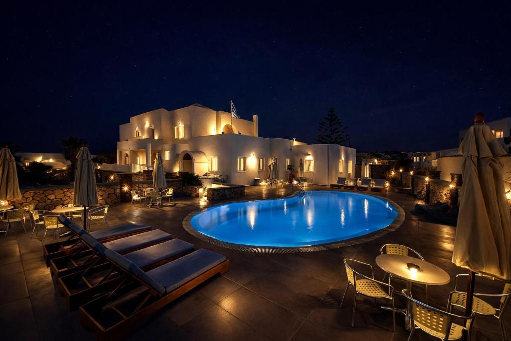 a large swimming pool at night with tables and chairs at Babis Hotel in Karterados