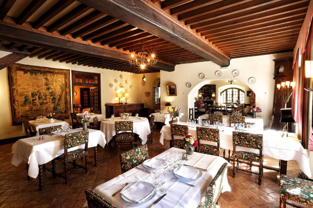 ein Esszimmer mit weißen Tischen und Stühlen in der Unterkunft Hostellerie du Vieux Pérouges in Pérouges