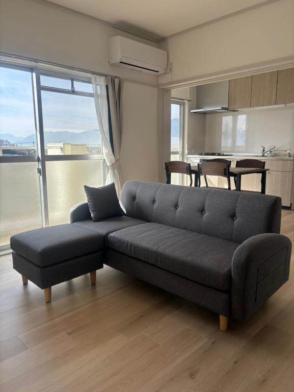 a black couch in a living room with a kitchen at OtowaBase in Kofu