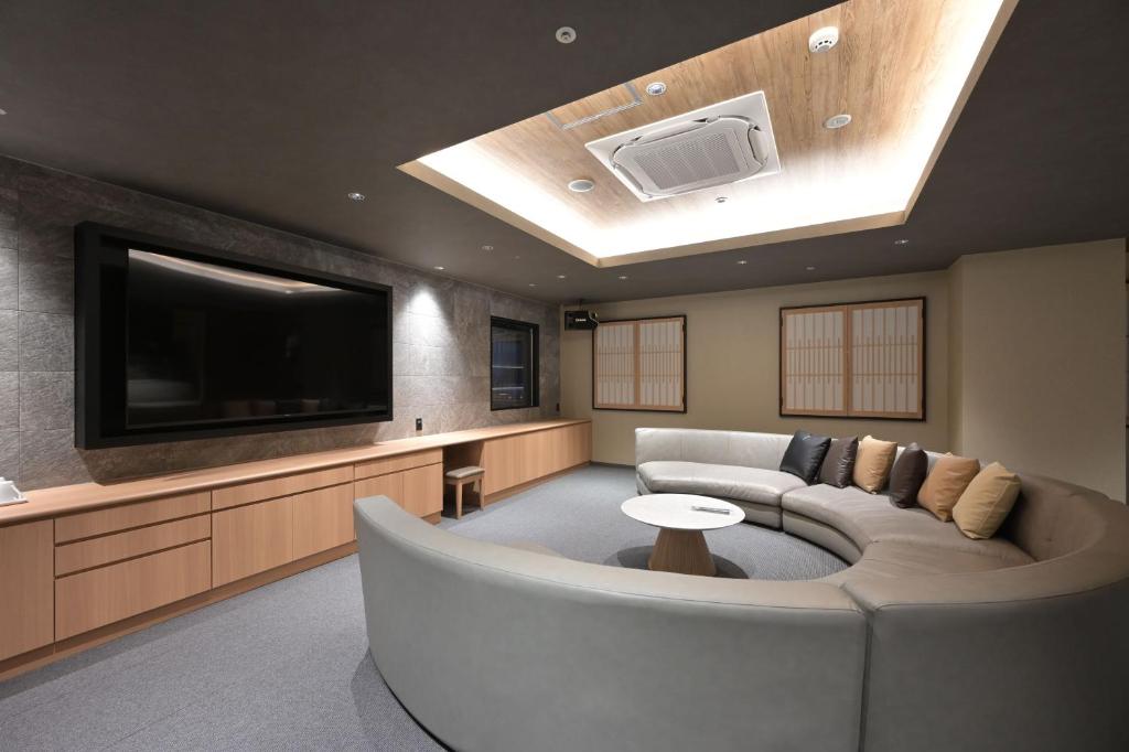 a living room with a couch and a flat screen tv at HOTEL THE7 Kumamoto in Kumamoto