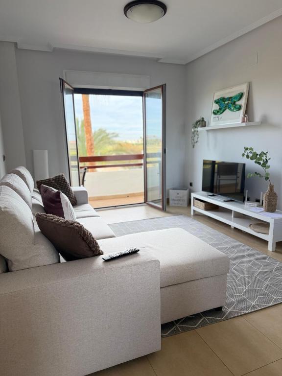 a living room with a white couch and a television at SunGolf Apartment in Los Alcázares