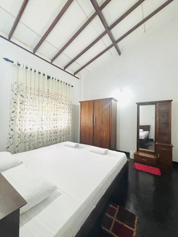 a bedroom with a large white bed and a wooden cabinet at HotelSide Residences in Negombo