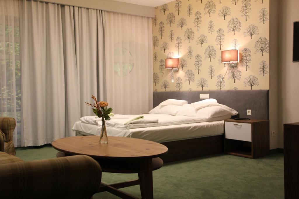 ソポトにあるHotel Leśnyのベッドとコーヒーテーブルが備わるホテルルームです。