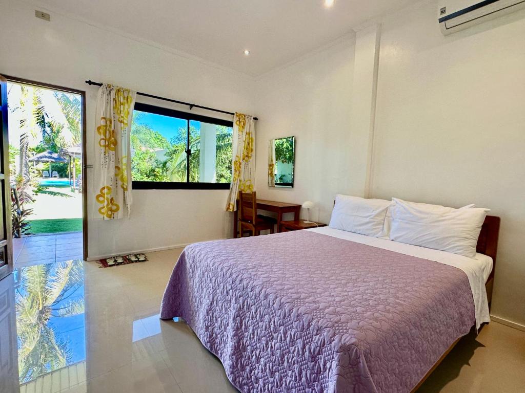 a bedroom with a bed and a large window at Strutz Art Garden Resort in Bangued