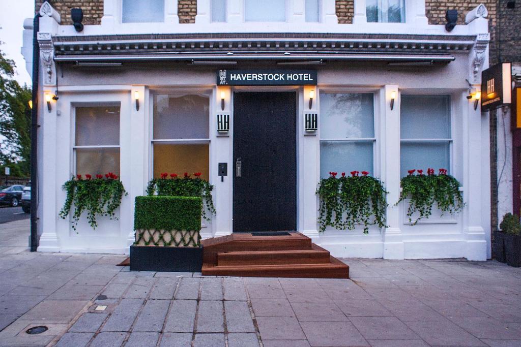 une maison blanche avec une porte noire et des fleurs rouges dans l'établissement NOX Belsize Park, à Londres