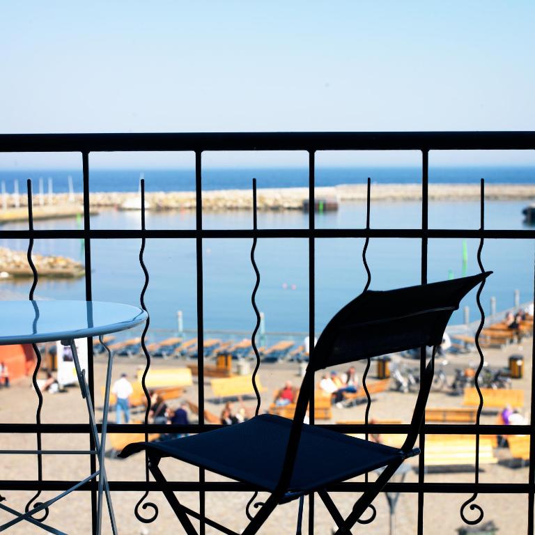 two chairs and a table on a balcony with a beach at Våningen vid Havet in Simrishamn