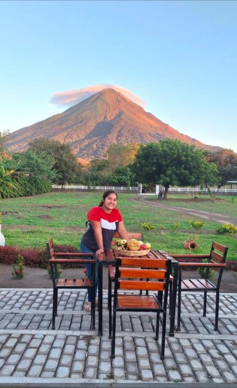 a woman sitting at a table in front of a mountain at Finca El Monasterio in Rivas