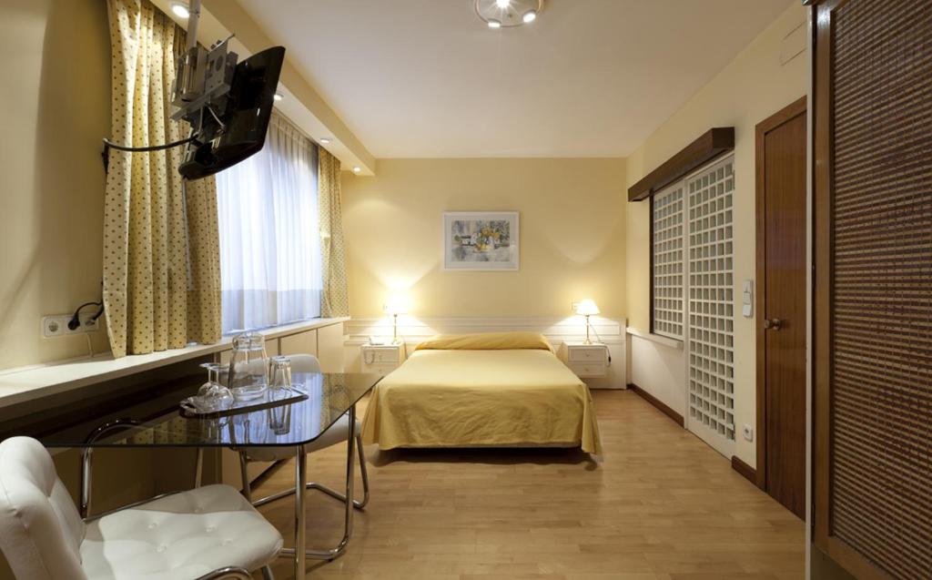 マドリードにあるアパルタメントス セントロ コロンのベッドとガラスのテーブルが備わるホテルルームです。