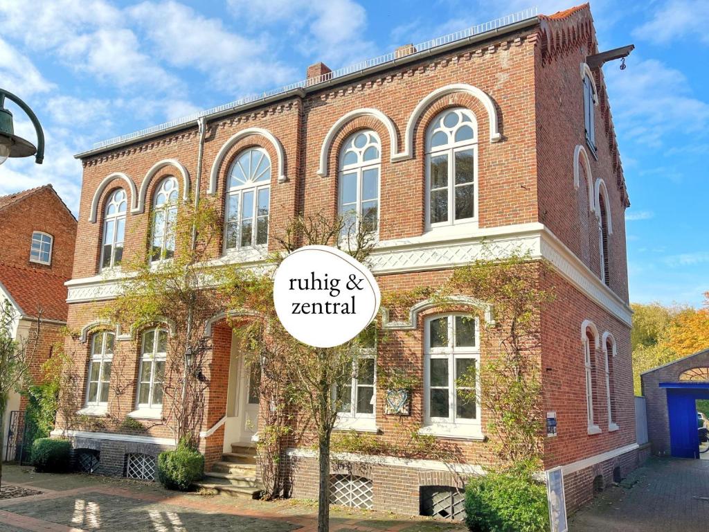 ein Backsteingebäude mit einem Schild davor in der Unterkunft FeWo "Ebbe" im historischen Denkmal, ruhig & modern mit Stil, Kunst und großem Garten, hochwertiger Ausstattung & zentraler Lage in Esens- 3km zur Nordsee, alles fußläufig erreichbar - ideal für Paare oder kleine Familien in Esens