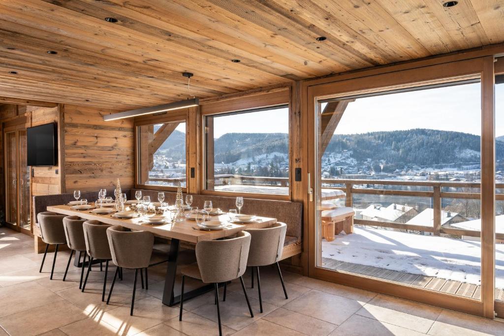 a dining room with a table and chairs and a large window at Sorelle Chalet, spa, indoor pool, lake view in Gérardmer