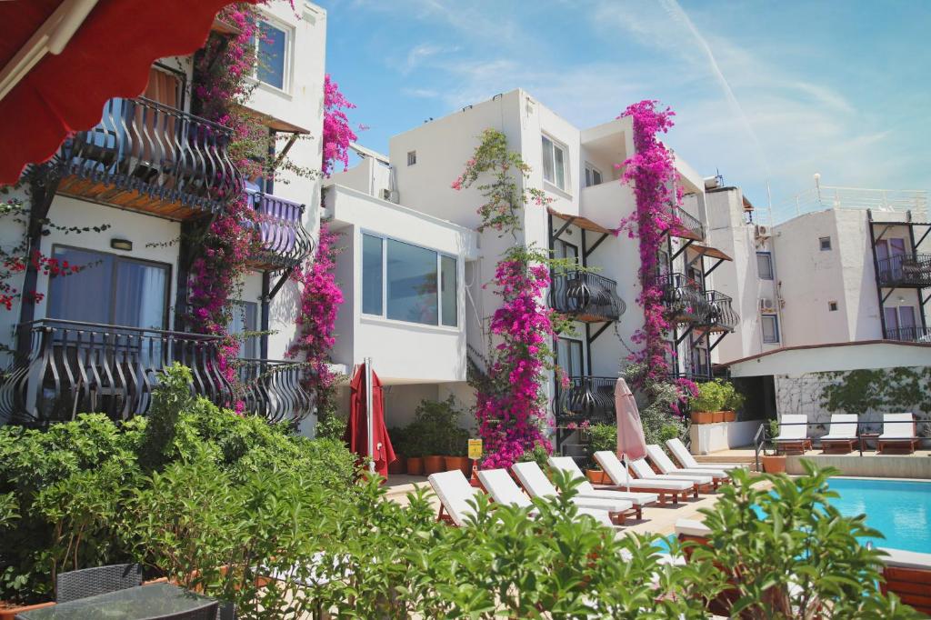 a hotel with a pool and chairs and flowers at Hotel Gumbet in Bodrum City