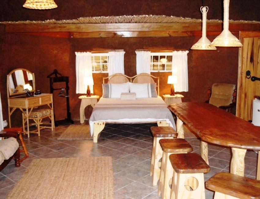 um quarto com uma cama, uma mesa e um espelho em The Funny Farm Shire em Duiwerivier