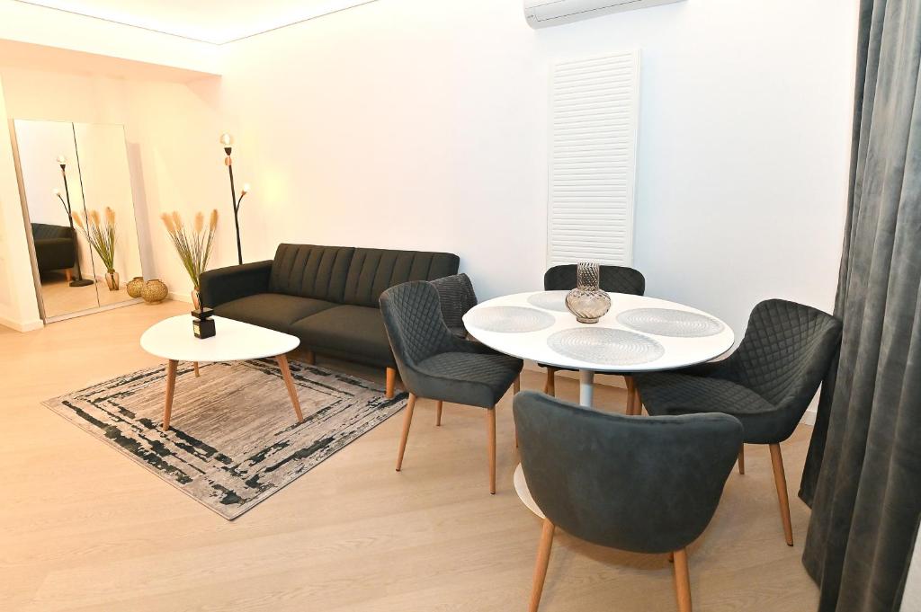 a living room with a couch and a table and chairs at Cortina Nord Panoramic Studio in Voluntari