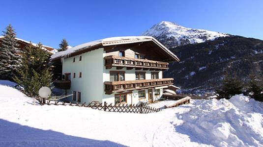 ein Gebäude auf einem verschneiten Hügel mit einem Berg in der Unterkunft Gästehaus Veit Fiegl in Sölden