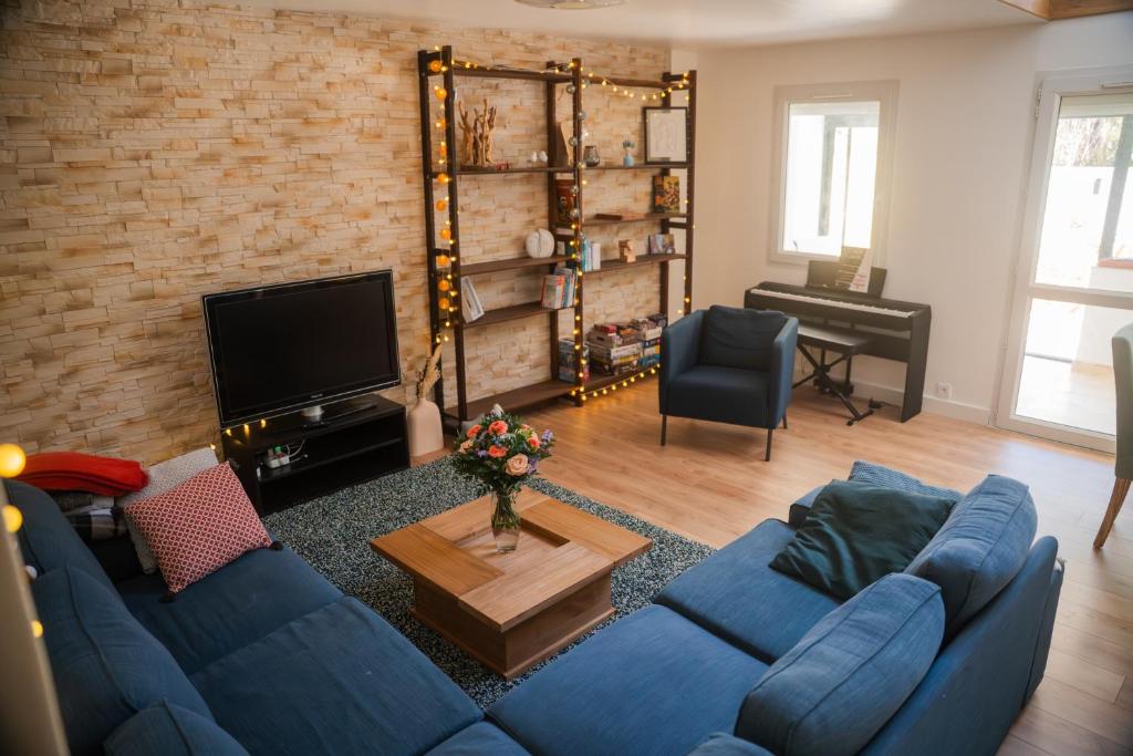 a living room with a blue couch and a television at Le Cocon du Golf in Nîmes