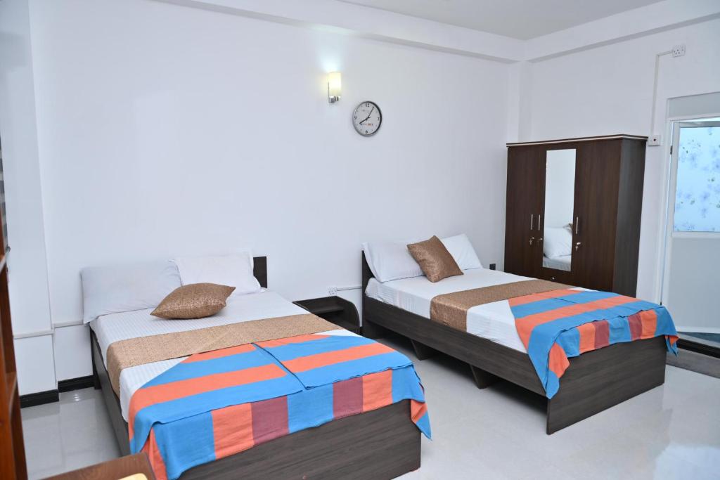 a bedroom with two beds and a clock on the wall at Hureshan Villa in Negombo