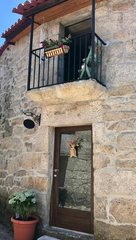 ein Steingebäude mit Tür und Balkon in der Unterkunft Casa Media Lúa in Allariz