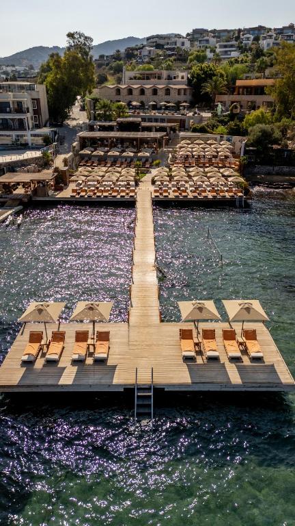 a dock with chairs and umbrellas in the water at Ruins Luxury Resort - Adults Only in Yalıkavak