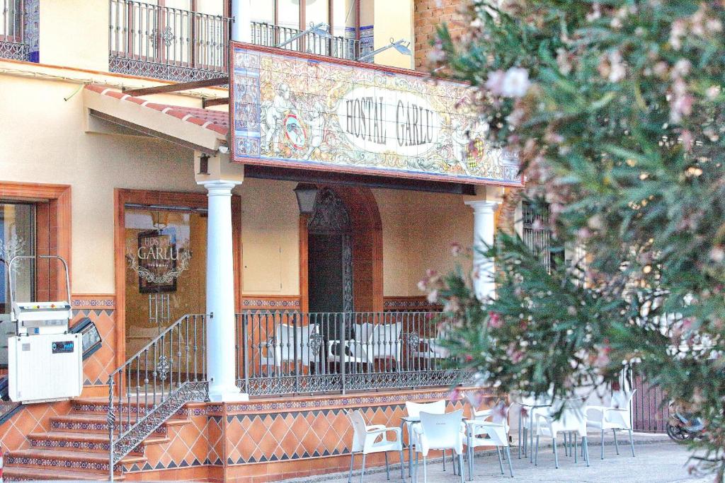 een gebouw met een balkon met tafels en stoelen bij Hostal Garlu in La Rambla