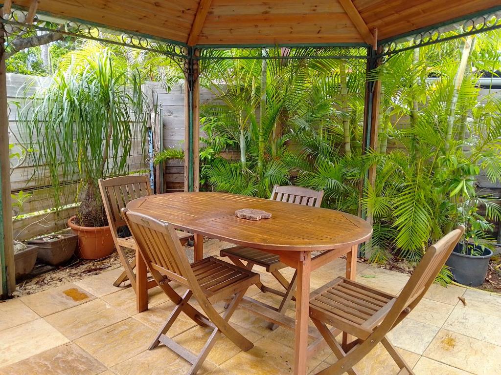 a wooden table and chairs on a patio with plants at Saline les bains petite maison bien aménagée calme & plage à pied in La Saline les Bains