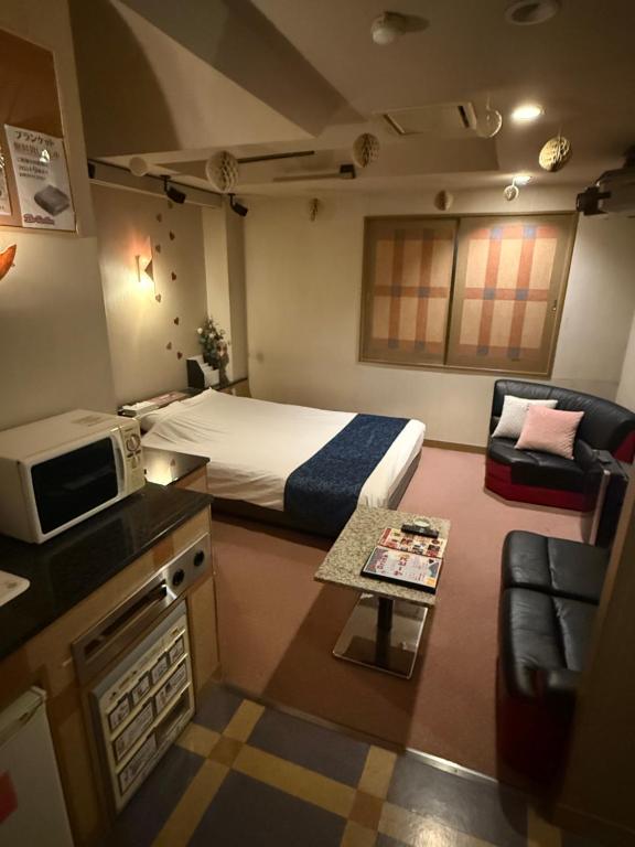 a room with a bed and a kitchen with a microwave at HOTEL Bew Rose Mary in Kai
