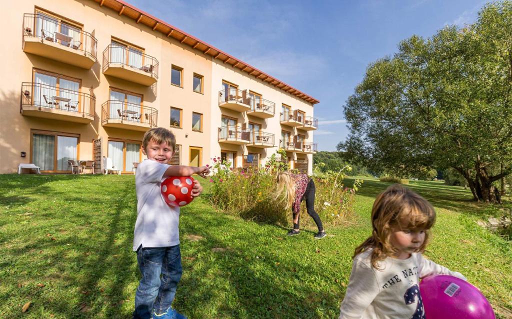 two children playing with balls in the grass in front of a building at Familien Hotel Krainz in Loipersdorf bei Fürstenfeld