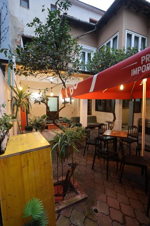 a patio with an umbrella and tables and chairs at Villa 18 Hostel in Tirana