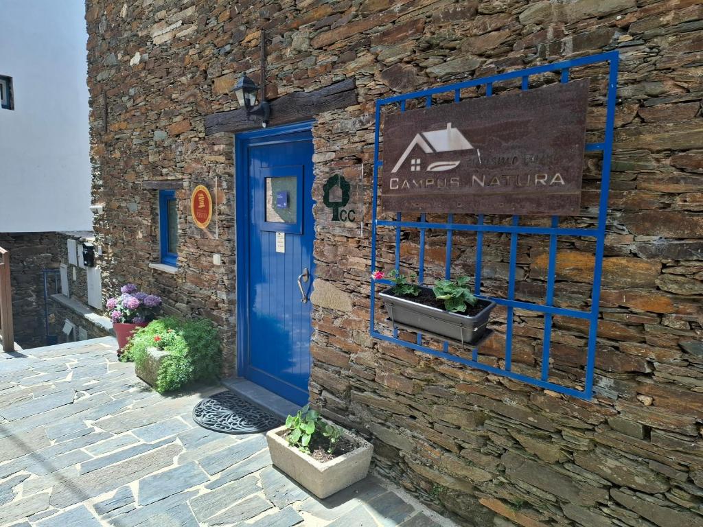 a blue door on a stone building with plants at Campus Natura in Arganil