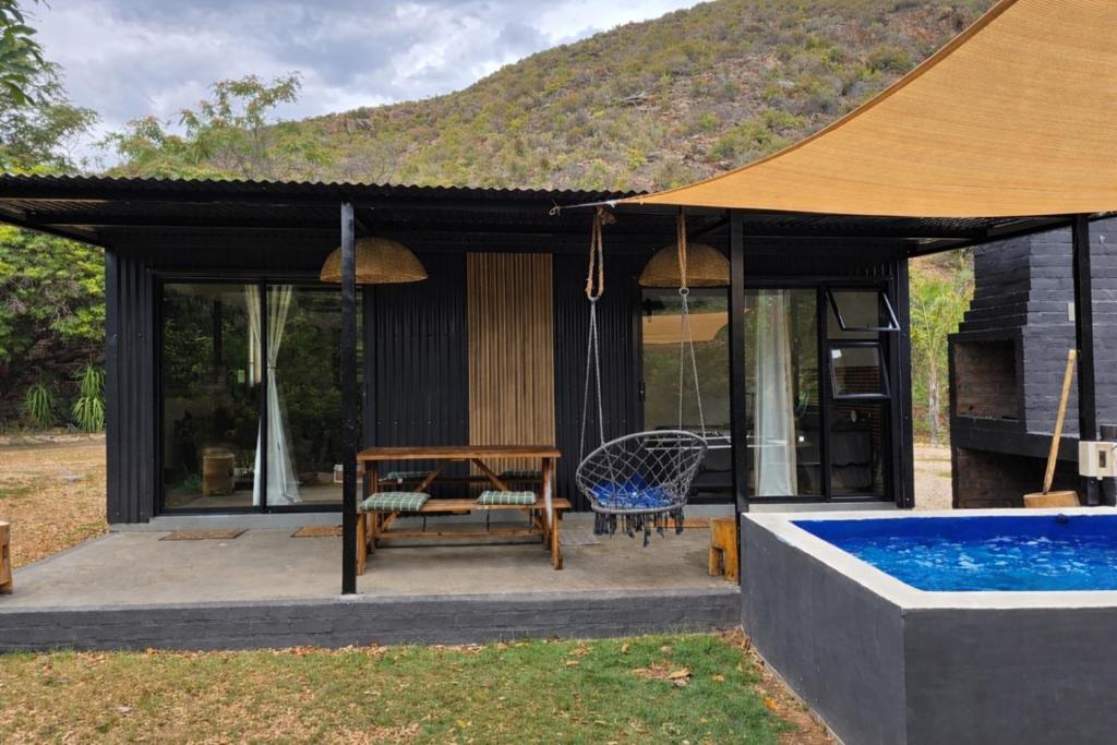 a house with a pool and a table and a chair at Luxury Unit with Mountain Views & Splash Pool in Oudtshoorn