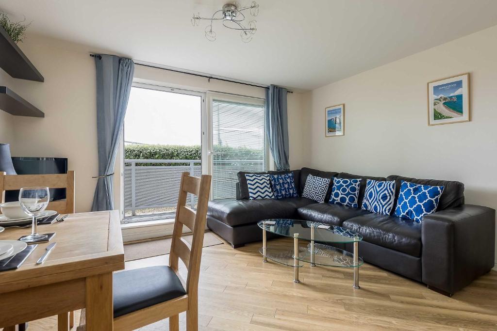 a living room with a black leather couch and a table at Bay Retreat- Moments from Hamworthy Park in Poole