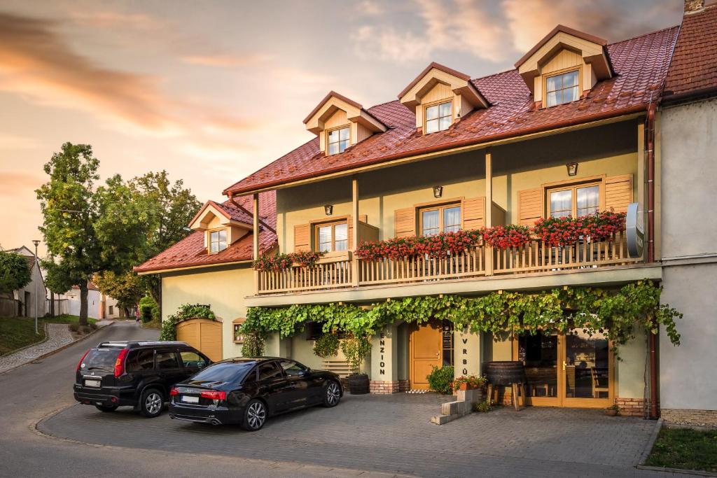 two cars parked in front of a large house at Penzion a vinařství U Vrbů in Hustopeče