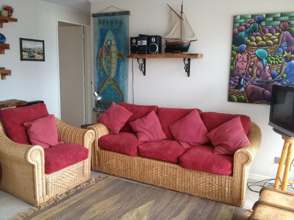 a living room with a red couch and two chairs at Horcon Condominio CAUCAU in Horcón