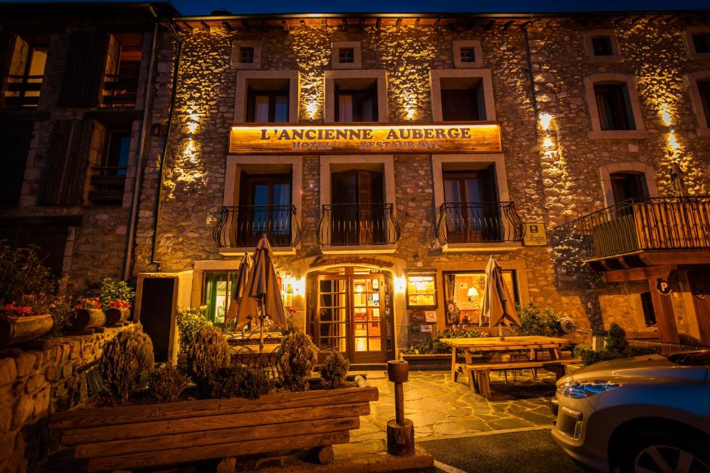 a hotel with a sign on the front of it at night at Logis Hôtel Restaurant L'ancienne Auberge in Bolquere Pyrenees 2000