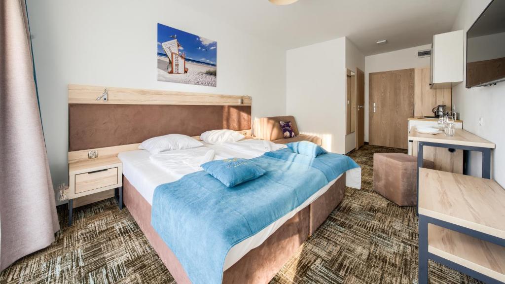 a bedroom with a large bed with blue sheets at Welle Resort, Sun & Snow in Grzybowo