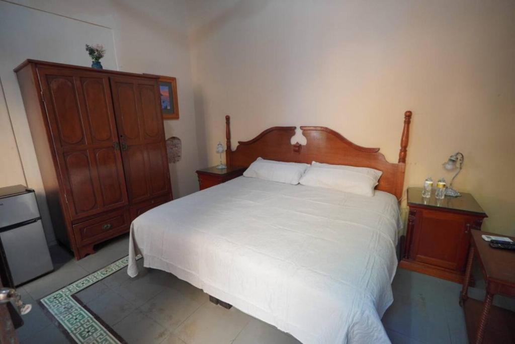 a bedroom with a large white bed and a wooden dresser at Habitacion Faro in Mazatlán