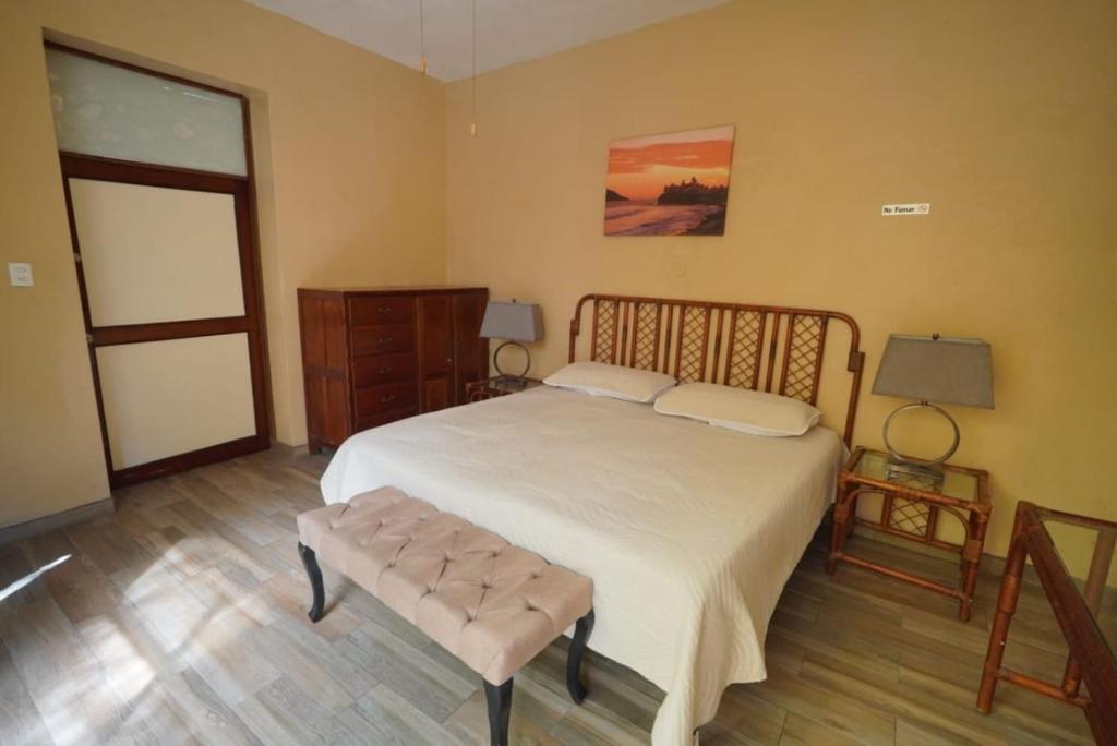 a bedroom with a large white bed and a table at Habitacion Machado in Mazatlán