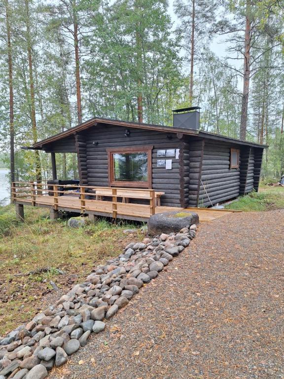 a log cabin in the woods with a rock path at Beautiful Cottage at Lake Saimaa, Rantamaja in Juva