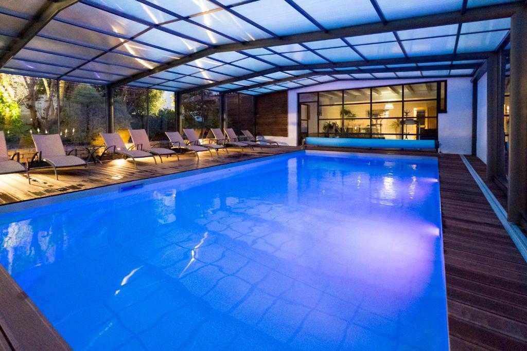 une grande piscine avec des chaises et un bâtiment dans l'établissement Hôtel de La Marée - Face à l'océan - Ile de Ré, à Rivedoux-Plage