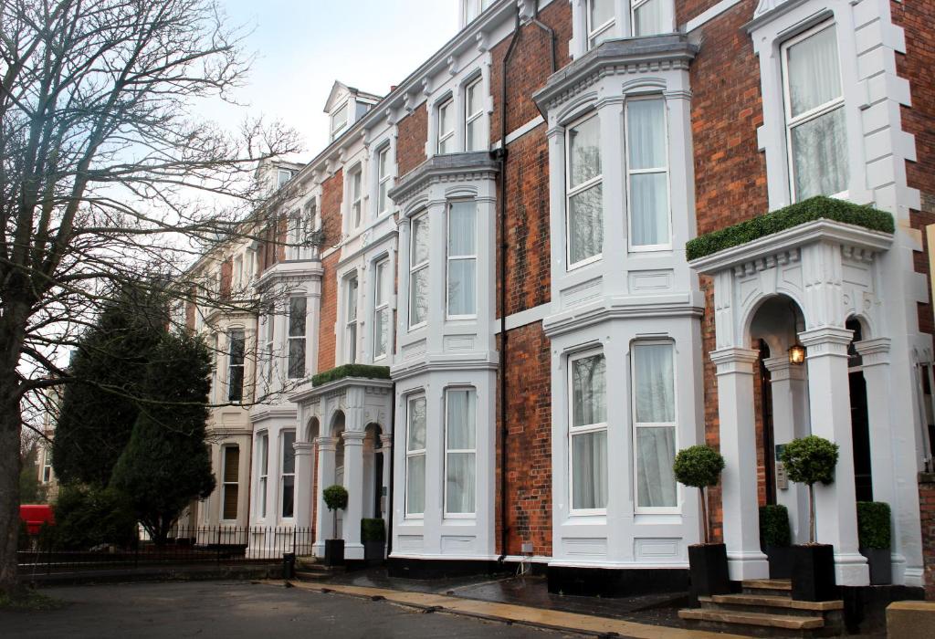 a row of houses with white windows on a street at 91 Aparthotel Jesmond Road in Newcastle upon Tyne