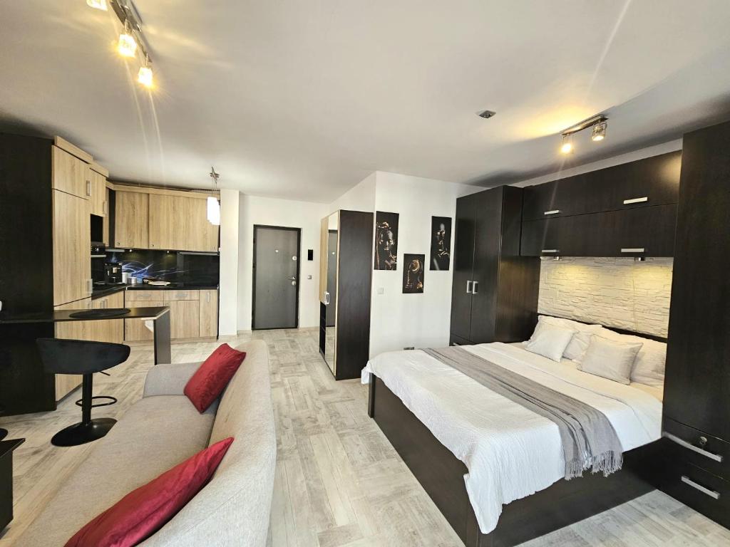 a bedroom with a bed and a couch and a kitchen at The Solstice Studio Apartment in Cluj-Napoca